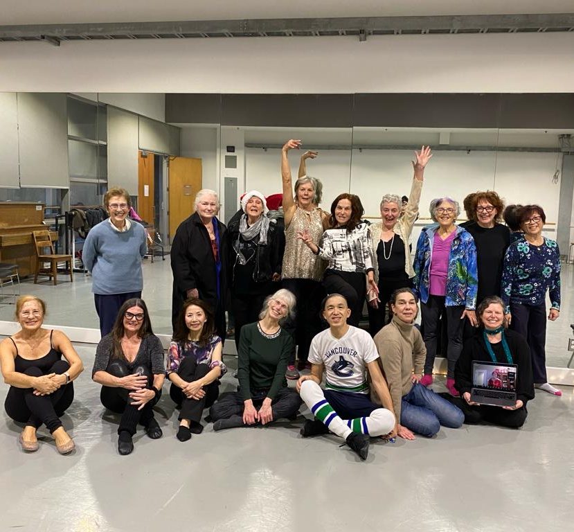 Group photo of the Power of Dance Seniors class: a number of seniors in dance class clothes stand and sit together smiling at the camera.